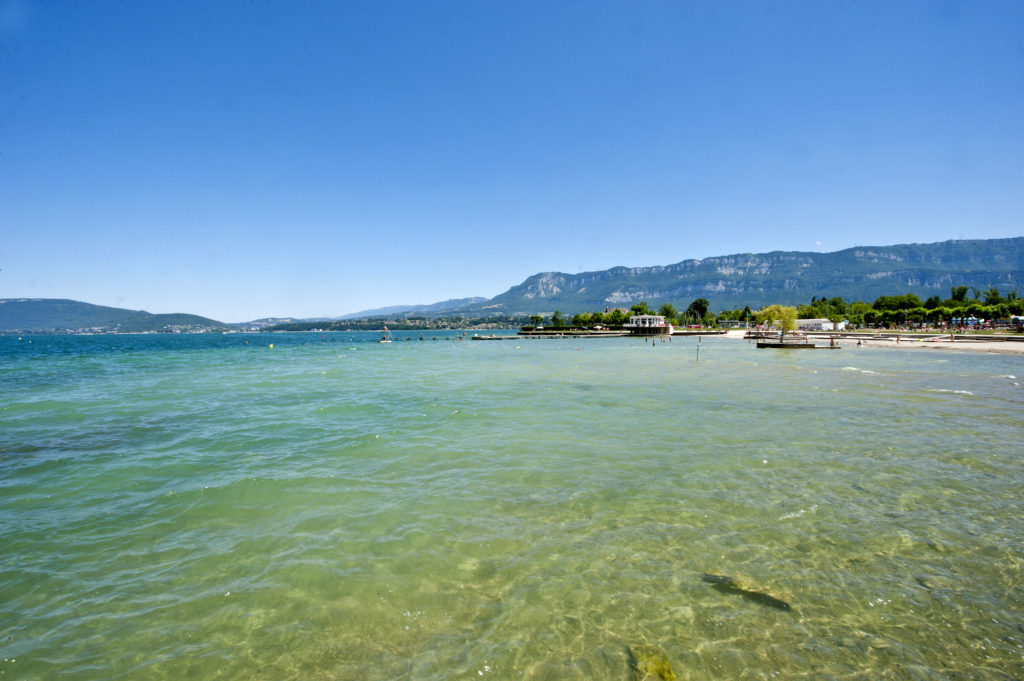 Plage aux eaux turquoise sur la rive du lac du Bourget